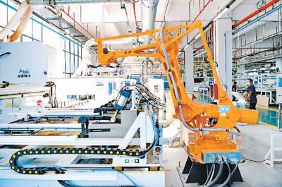7月1日,江西省赣州市南康区家具零部件共享配料制作中心的工人在数字化生产线导入编程代码,遥控操作机械臂、传送带和数控切割机等智能设备加工零件。 朱海鹏摄(人民视觉)